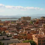 View over the rooftops and domes of Cagliari old town toward the sea, southern Sardinia