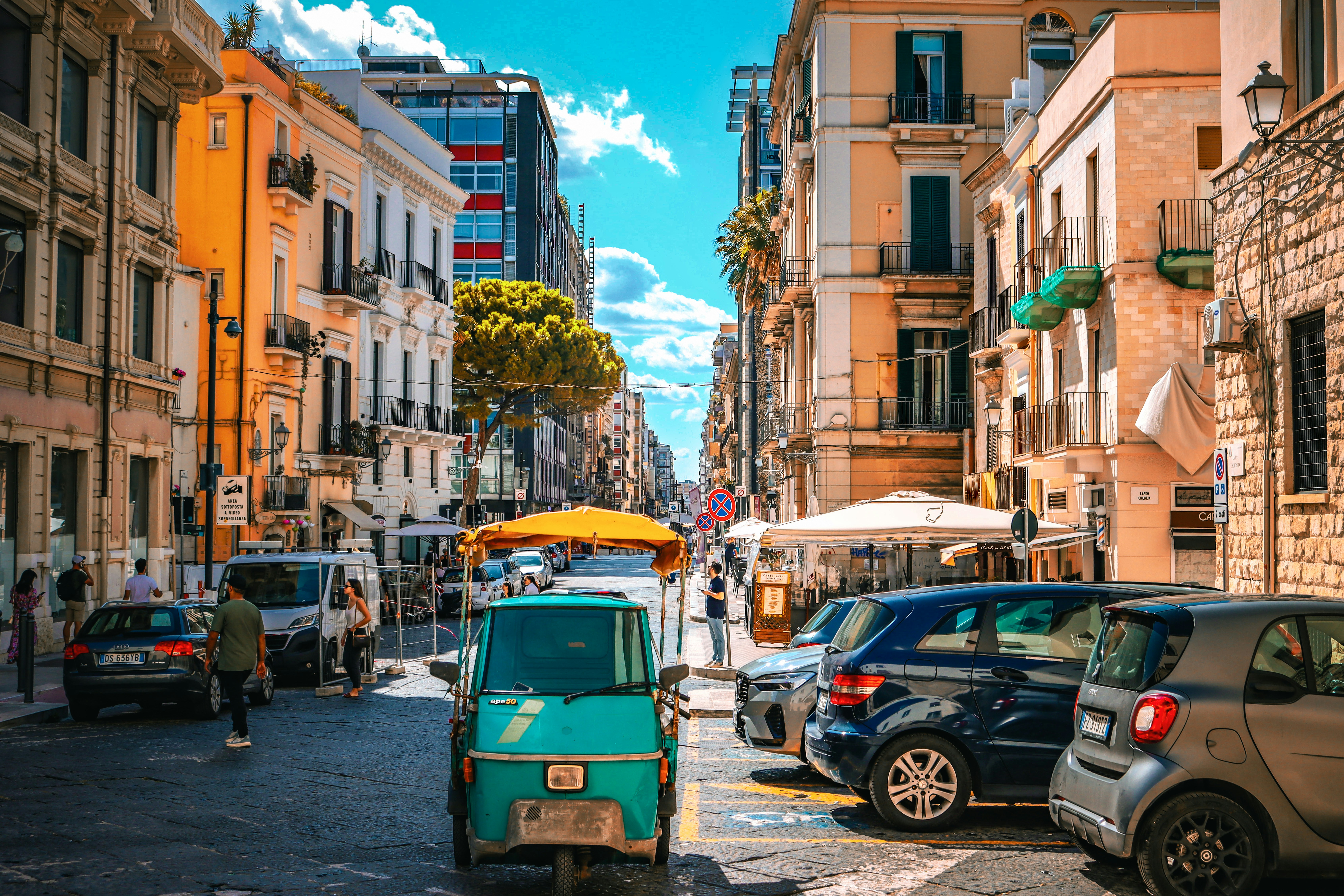 Narrow city street in Bari filled with parked cars, typical of the paid parking zones outside the ZTL