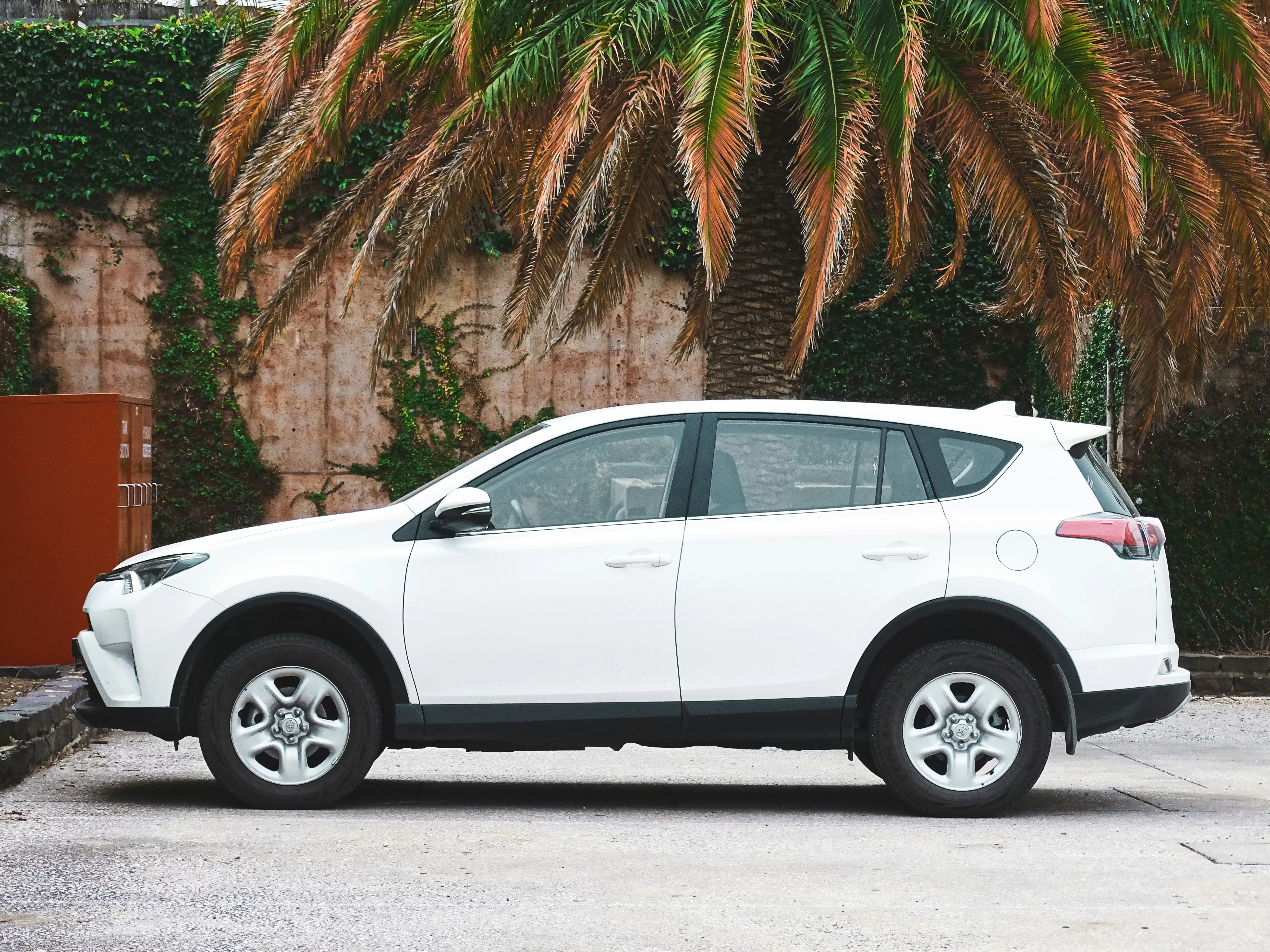 White car parked near palm trees in a quiet guarded lot, the safe way to park in Campania