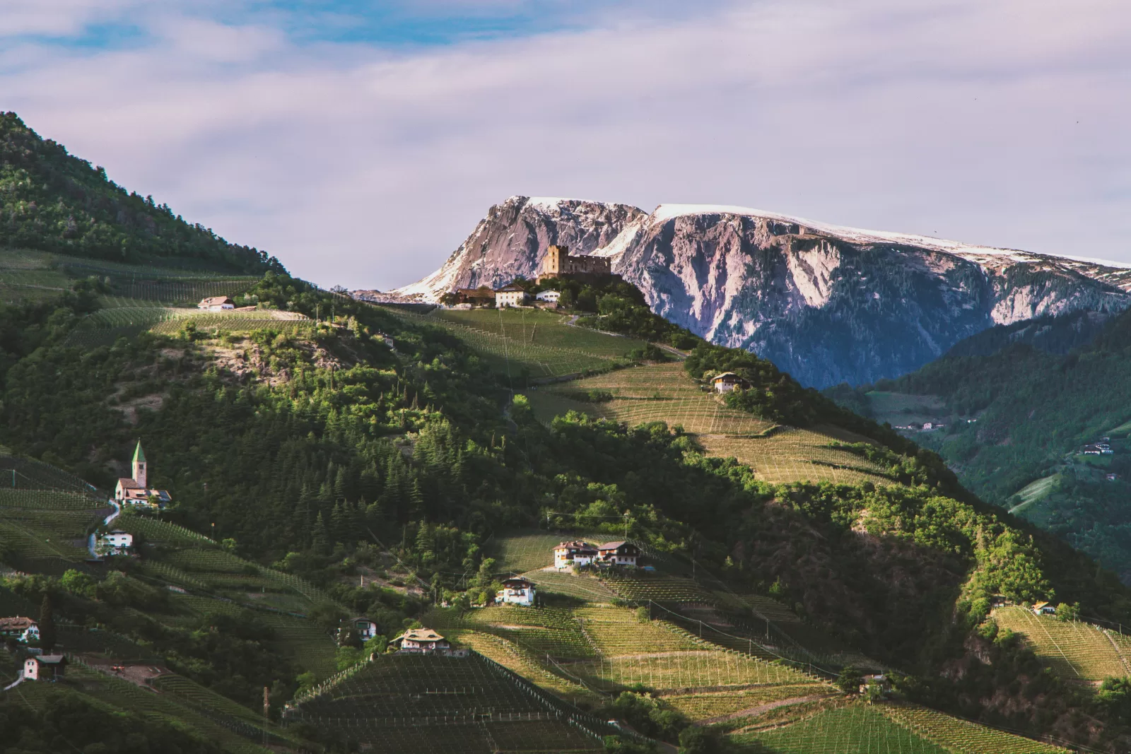 Winnice i zamek na wzgórzu nad Bolzano, a w tle Dolomity, około 151 km autostradą A22 od lotniska Werona