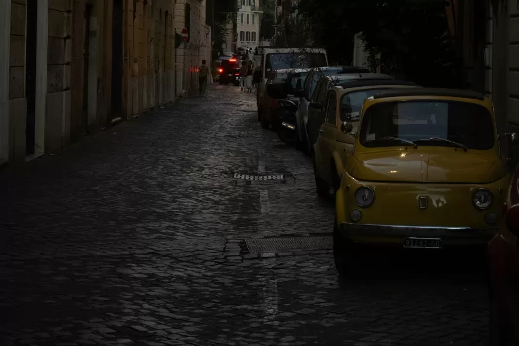 A yellow Fiat 500 parked on a street in Rome, where much of the historic centre is a ZTL zone