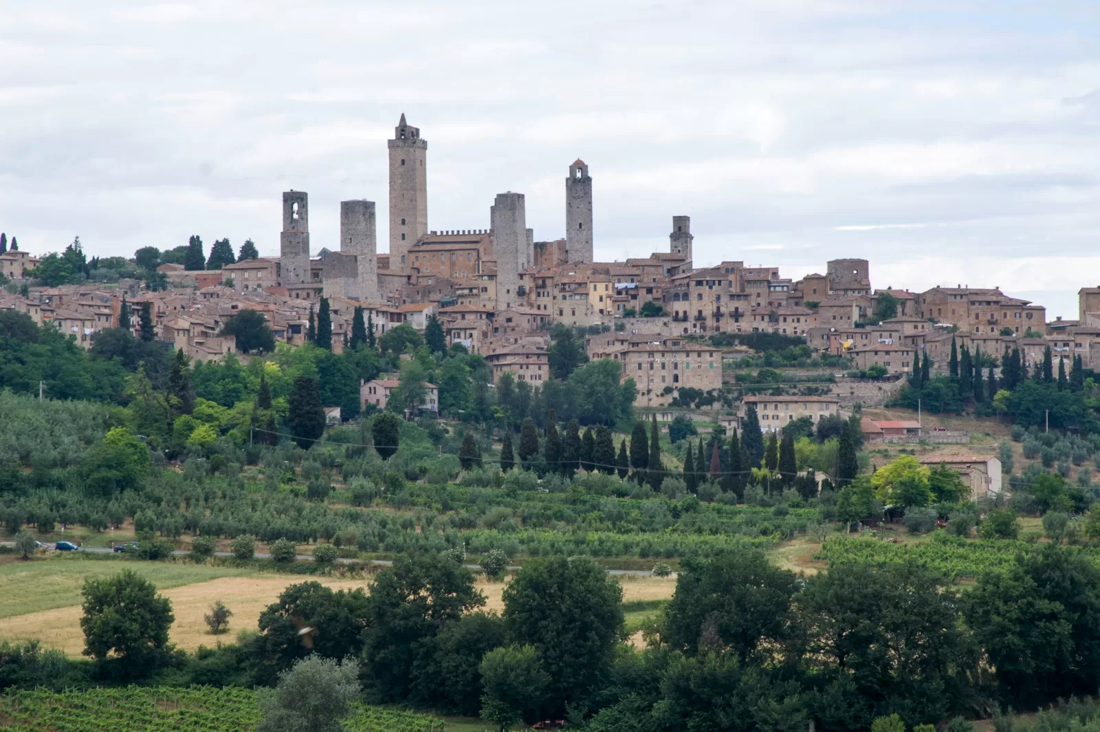 San Gimignano viduramžių bokštai virš vynuogynų ir alyvmedžių giraičių, maždaug 1 valanda 5 minutės kelio automobiliu nuo Florencijos oro uosto